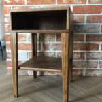 Szafka nocna Dora ze sklejki w jasnym odcieniu, wyposażona w jedną pojemną szufladę. Kompaktowy mebel do nowoczesnych wnętrz.