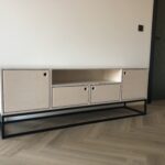 Solidna komoda z jasnej sklejki, z prostymi liniami i delikatnymi uchwytami. Praktyczny i estetyczny wybór do wnętrz w stylu boho.